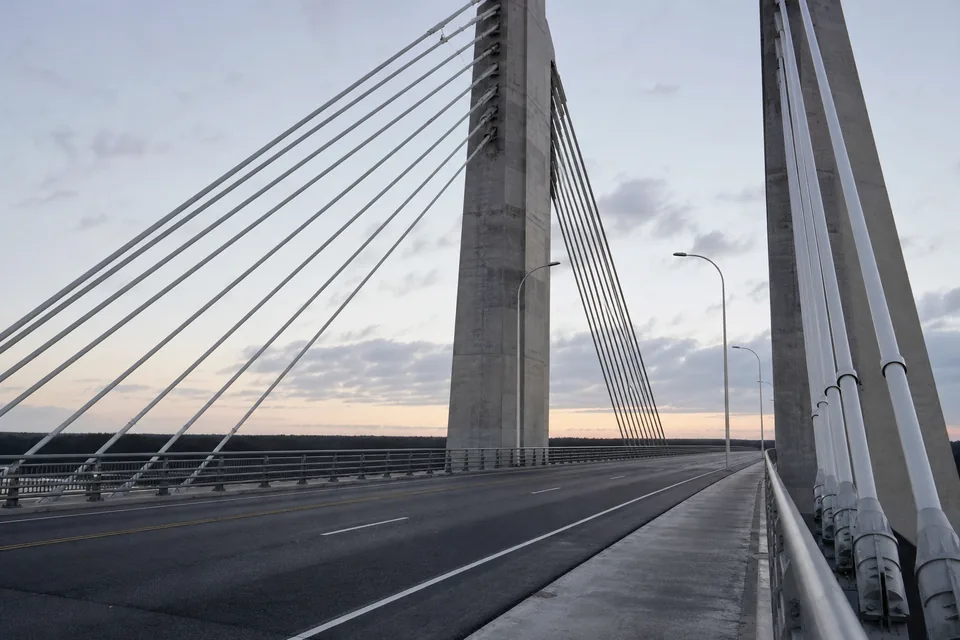 Cable-stayed concrete bridge at dawn, viewed along the deck toward the pylons